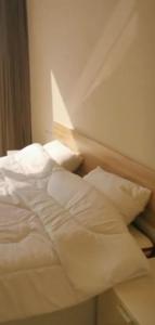 łóżko z białą pościelą i poduszkami w pokoju w obiekcie Salalah Forest Island Villa w mieście Ţāqah