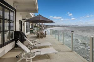 balcone con sedie, ombrellone e oceano di ৎ୭ Victoria ৎ୭ a Malibu