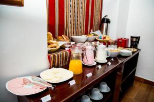 una mesa de desayuno con comida y zumo de naranja. en Hotel Casablanca en Ollantaytambo