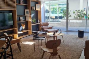 een woonkamer met een tv, stoelen en tafels bij Apartamento nuevo super full in Punta del Este