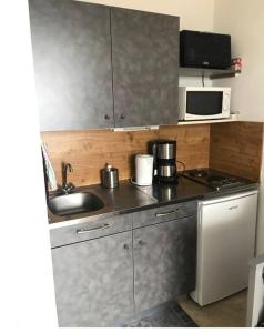 a small kitchen with a sink and a microwave at Appartement 6 couchages aux pieds des pistes in Chamrousse