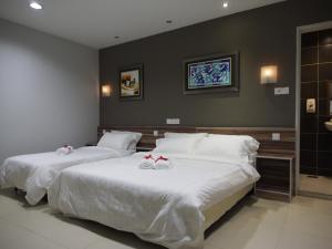 two beds in a hotel room with bows on them at One Avenue Hotel Balakong in Seri Kembangan