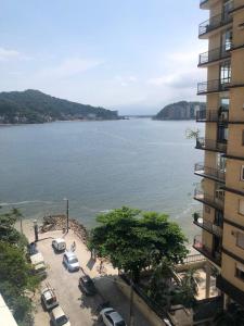 a large body of water with cars parked next to a building at Studio com bela vista para o mar in São Vicente