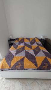 Una cama con una manta de colores encima. en Studio com bela vista para o mar en São Vicente