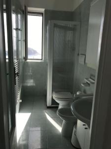een badkamer met 2 toiletten, een wastafel en een raam bij Il Fico “Villa Nunzia” in Ischia