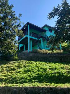 a house on a hill with trees in front of it at Villa Fe Esperanza - Vistas al Valle de Constanza in Constanza