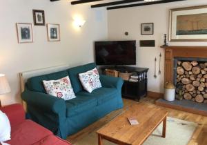 un soggiorno con un divano blu e un camino di Pontfair - Charming Cottage 10 mins walk from beach a Llangrannog