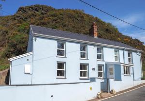 una casa bianca con una collina sullo sfondo di Pontfair - Charming Cottage 10 mins walk from beach a Llangrannog