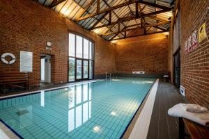 a swimming pool in a building with a brick wall at Wagtail in Fakenham