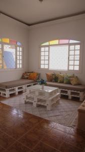 uma sala de estar com um sofá, uma mesa e janelas em Hostel Litoral em Peruíbe