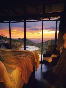 a room with a bed and a view of a sunset at Paraiso Del Cielo in San Ramón