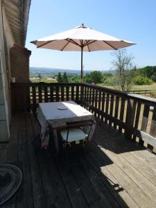 Puy-lʼÉvêque的住宿－Domaine de la Borde，木甲板上的桌子和遮阳伞