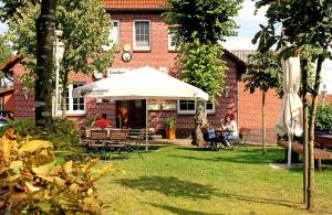 a group of people sitting under an umbrella in front of a building at Hotel Zur Linde in Neddenaverbergen