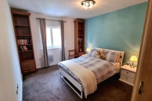 a bedroom with a bed and a blue wall at Specious Parkview Apartment, 4 Mins Walk to Underground in Barkingside