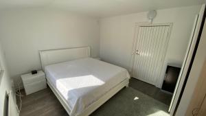 a small white bedroom with a bed and a door at Videdal apartment 2 rooms in Malmö