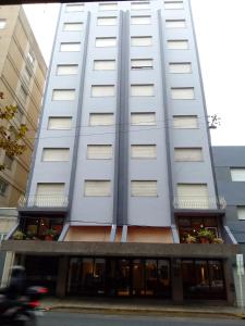 a tall white building with windows on a street at Hotel Cosmos in Mar del Plata