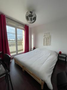 a bedroom with a large bed and a large window at Beau F2 du hameau avec parking in Meaux
