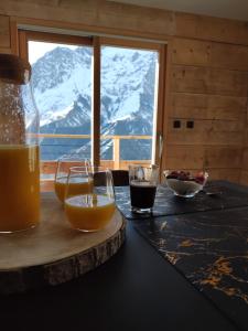 a table with two glasses of orange juice and a window at Chalet La Gave/La Meije in La Grave