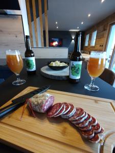 ein Schneidebrett mit Fleisch und zwei Gläsern Wein in der Unterkunft Chalet La Gave/La Meije in La Grave