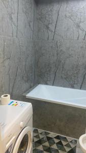 ein Badezimmer mit einer Badewanne und einer Waschmaschine in der Unterkunft МЕГА АЛЬФРАБИ in Almaty