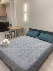 Schlafzimmer mit einem Bett mit blauen Kissen und einem Tisch in der Unterkunft МЕГА АЛЬФРАБИ in Almaty