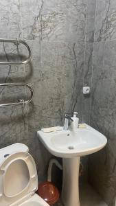 ein Badezimmer mit einem weißen Waschbecken und einem WC in der Unterkunft МЕГА АЛЬФРАБИ in Almaty