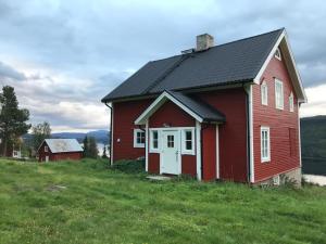 8 bed house in Vik, Åre في آرا: منزل احمر بسقف اسود على ارض خضراء