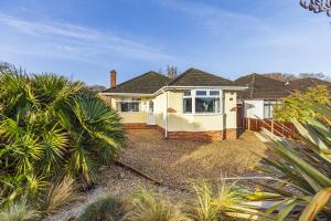 a white house with palm trees in front of it at Cozy Cottage, Secure Garden, Dog Freindly in Bournemouth