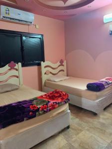 two beds in a room with pink walls at فيلا بالعلا in AlUla
