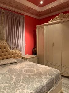 a bedroom with a large bed and a red wall at فيلا بالعلا in AlUla