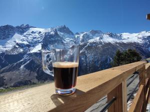 ein Glas Bier auf einer Holzschiene mit Bergen in der Unterkunft Chalet La Gave/La Meije in La Grave