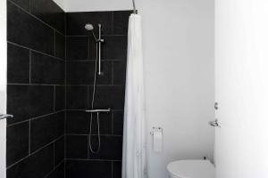 uma casa de banho com um chuveiro, um WC e uma cortina de chuveiro. em Summer Holiday Apt, No, 2 At Beautiful Solgaarden em Svaneke