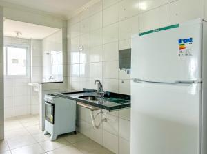 eine weiße Küche mit einer Spüle und einem Kühlschrank in der Unterkunft Apto a beira mar da Praia de Vera Cruz,Mongagua SP in Mongaguá