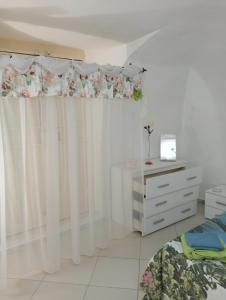 ナポリにあるIl cuore di Napoliのベッドルーム(白いカーテン、ベッド1台、ドレッサー付)