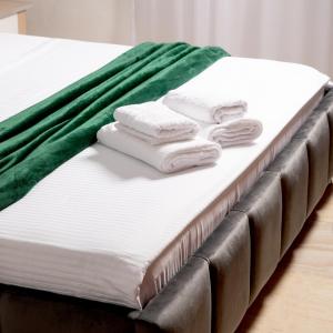 - un lit avec des serviettes blanches et une couverture verte dans l'établissement Maris Apartment, à Tirana