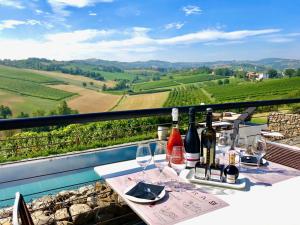 una mesa con copas de vino y botellas de vino en el balcón en Agriturismo Opera 02, en Castelvetro di Modena