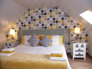a bedroom with a large bed with yellow and gray pillows at Kirkside in Auchterarder