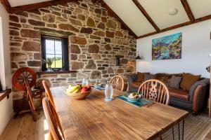 a wooden table in a living room with a stone wall at The Wreck - Lochside cottage Dog Friendly in Ullapool