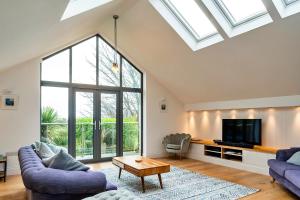 a living room with two purple couches and a tv at Finest Retreats - Dingles Cottage in Philleigh