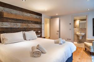 ein Schlafzimmer mit einem großen weißen Bett und einer Holzwand in der Unterkunft Finest Retreats - Dingles Cottage in Philleigh