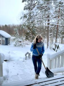 a woman with a shovel in the snow at Blueberry Villa at Saimaa Lakeside in Taipalsaari