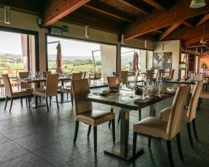 una sala da pranzo con tavolo, sedie e finestre di Agriturismo Opera 02 a Castelvetro di Modena