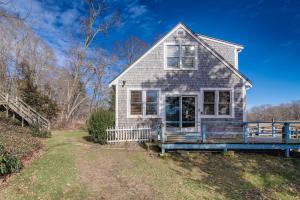 a white house with a porch on a hill at Riverfront Kingston Cottage w/ Deck, 2 Mi to Beach in Kingston