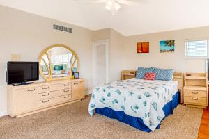 a bedroom with a bed and a flat screen tv at Breezy Palms & Tropical Charm in Key Colony Beach