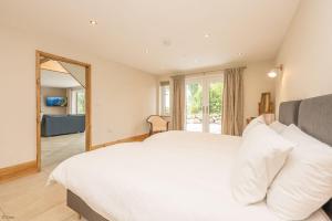 a bedroom with a large white bed and a mirror at Maes-Y-Caerau in Criccieth