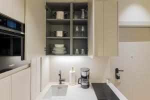 a kitchen with white cabinets and a sink at Rio by Wynwood House in Madrid