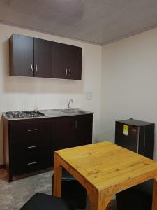 cocina con mesa de madera, fogones y fregadero en GREEN APARTMEN "El Jardín", en Girón