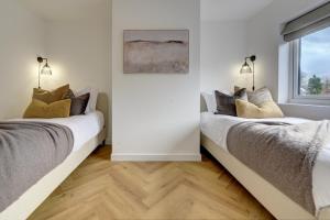 two beds in a white room with a window at Kist Accommodates presents - Hygge House in Ripon
