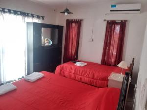 2 Betten in einem Zimmer mit roter Bettwäsche und einem TV in der Unterkunft Cabañas El Abuelo in Belén