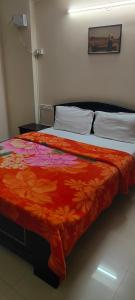 a bedroom with a bed with an orange blanket at Service Apartment Near Rameshwaram Cafe Brookefield in Bangalore